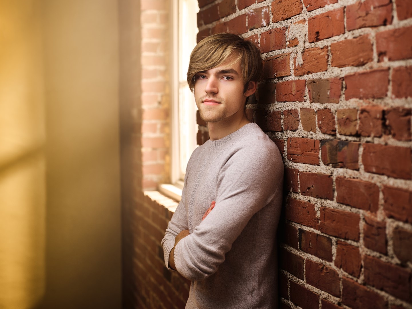 Photo of Harry in a sweater next to a brick wall